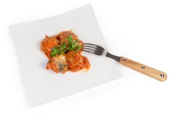 Canned fish in tomato sauce on dish with fork