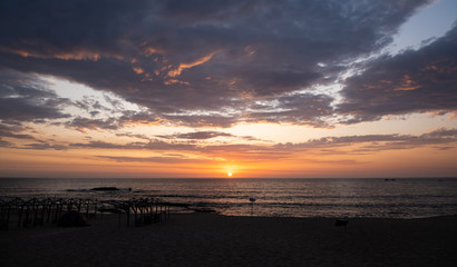 Sunset over beach in Povoa de Varzim, Portugal with beach hut frames in silhouette