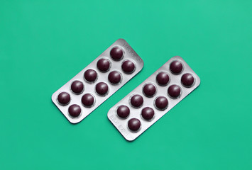 Set of pills blisters isolated on solid turquoise green background. Medical concept. Potent drugs. Brown pills.