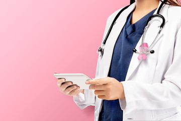 A woman doctor in a white lab coat with a pink ribbon and a stethoscope holding a tablet with a pink background - Powered by Adobe