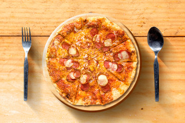 Pizza with spoon and fork on wooden table background