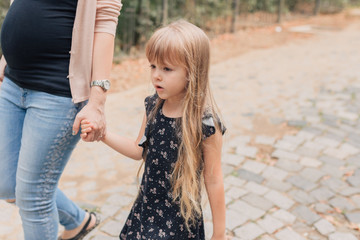 Naklejka premium pregnant woman and daughter walking in forest