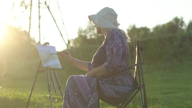 an elderly woman draws in nature