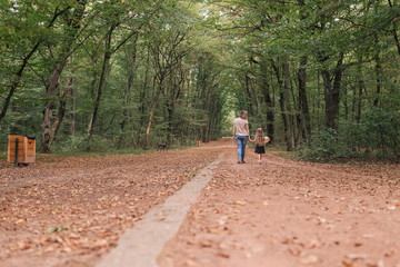 Obraz premium pregnant woman and daughter walking in forest