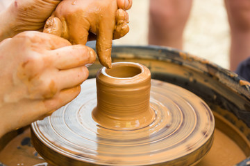 A close up view on ceramic production process on potter's wheel with children. Clay crafts with kids concept.