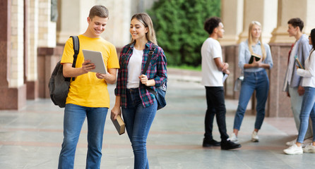 Classmates preparing for lecture with digital tablet outdoors