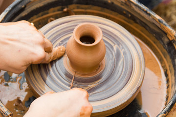 A close up view on ceramic production process on potter's wheel with children. Clay crafts with kids concept.