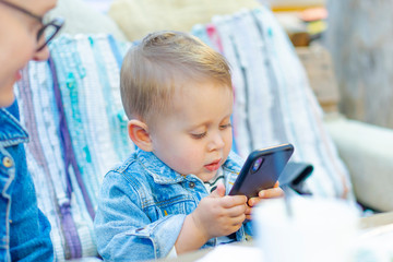 Young cute blonde baby boy with smartphone
