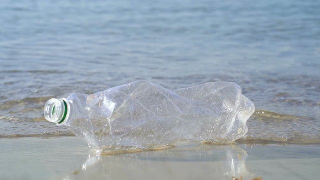 Plastic bottle literring and the clean beach. Slowmotion.