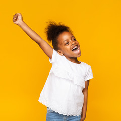 Cute african toddler girl shouting hooray on orange background