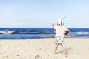 Cute baby girl pointing her finger on the ocean