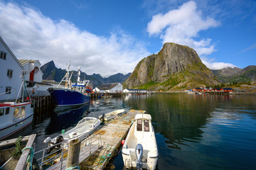 A fishing village at Hamnoy Reine, Norway during the daytime. The blue skies and mountains reflect the water.