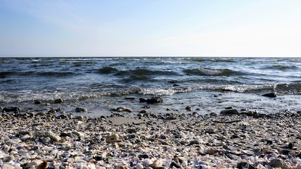 Front view of a wave on the sea from the beach with pebbles on it.