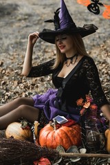 Halloween holiday witch Lady in Mystical atmosphere with a pumpkin outdoors, celebrate autumn 