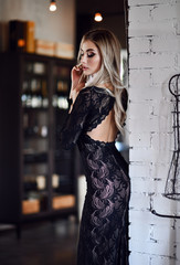 Pretty and successful beautiful brunette young woman in fashion black dress posing in expensive restaurant