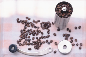 The coffee beans are in an antique hand-cranked coffee bean grinder, the kitchen tablecloth background in natural light, Selcetive focus, Vintage style.