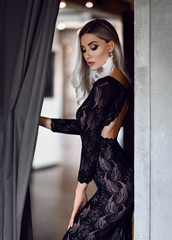 Pretty and successful beautiful brunette young woman in fashion black dress posing in expensive restaurant