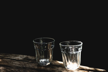 Couple clear glass on wood table with nature  light and black background, Selective focus.