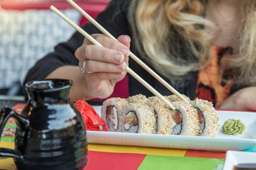 Woman eating sushi with chopsticks
