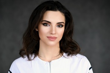 Fototapeta premium Concept large photo portrait of a cute pretty brunette girl with excellent make-up and good skin on a colorful background. Cosmetics, health, facial skin, beauty, art.