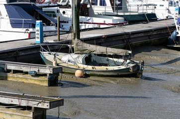 Old weathered yacht lying in the mud in the harbor