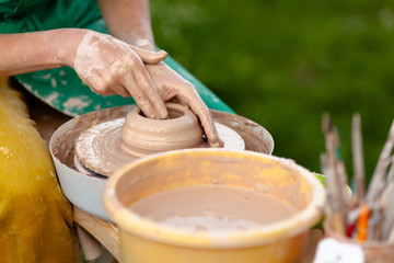 Hand craft making pottery on wheel. Female hands mold ceramic plate from clay (pot).
