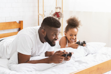 Obraz premium African man and his little girl playing on console with joysticks