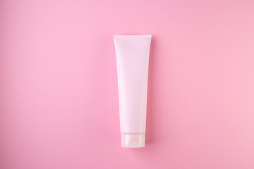 Plastic tube with face or body cream on pastel pink background