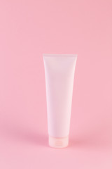 Plastic tube with face or body cream on pastel pink background