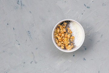 Bowl of homemade granola with yogurt and chia seeds on stone background from top view. Breakfast time