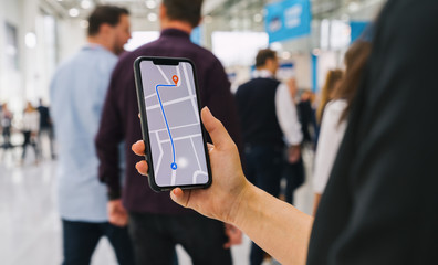 Visitor using GPS map navigation app on smartphone screen to get direction to destination address in the city, travel and technology concept image