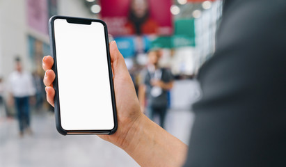 Female hand holding black cellphone with white screen at a trade fair, copyspace for your individual text.