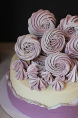 closeup lilac sugar meringue on a white and purple cake on dark background