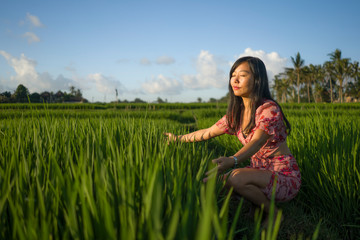 natural lifestyle portrait of young beautiful and relaxed Asian Korean woman in stylish Summer dress enjoying walk at tropical paradise rice field in eco tourism