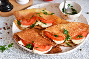 Pancakes with mozzarella and tomatoes with pesto on the kitchen table. Pancakes with caprese.