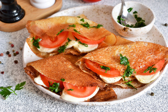 Pancakes with mozzarella and tomatoes with pesto on the kitchen table. Pancakes with caprese.