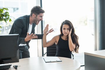 strict boss man swearing at upset tired employee woman for bad work at the workplace looking angry