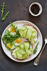 Lunch time. Bread toast with cheese, chopstick and cucumber on a concrete background. View from above.