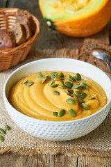 Thick pumpkin cream soup with seeds in a white bowl 