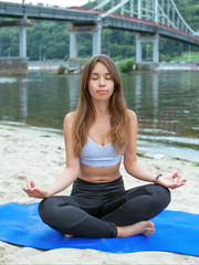 Fototapeta na wymiar young fit woman in sportwear in different yoga asanas outdoor on the beach by the river. Yoga and sport concept
