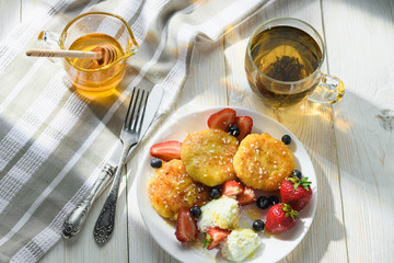cheesecakes with honey tea and berries on a wooden table