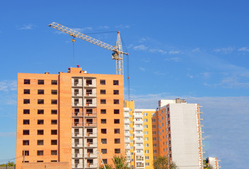 Fototapeta na wymiar Brick multistory building under construction with crane on the site, new condominium on background