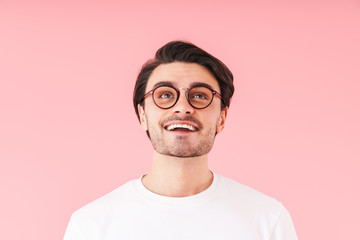Image of handsome cheerful man wearing eyeglasses smiling and looking upward at copyspace