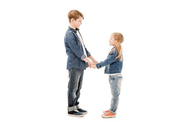 side view of kids holding hands and looking at each other isolated on white