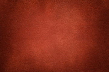 Background of dark orange suede fabric closeup. Velvet matt texture of ginger nubuck textile