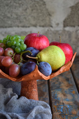 Autumn still life for thanksgiving with autumn fruits and berries on wooden background - grapes, apples, plums, viburnum, dogwood. Raw food. Copy space