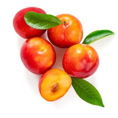 Isolated plums. Fresh Red plums with green leaves on white background. Top view. Flat lay