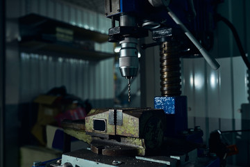 Drilling machine with a drill in the chuck and a vice in a car service.