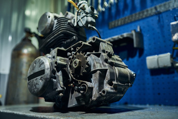 Faulty motorcycle engine on the desktop in a motorcycle workshop. Close-up.