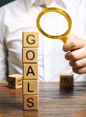 Wooden blocks with the word Goals and businessman. The concept of achieving business goal. Reaching...